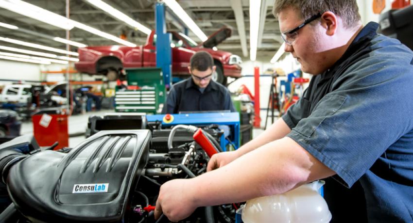 Student working on vehicle in shop